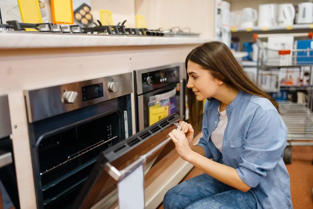 Woman choosing electric double oven or single in electronics store