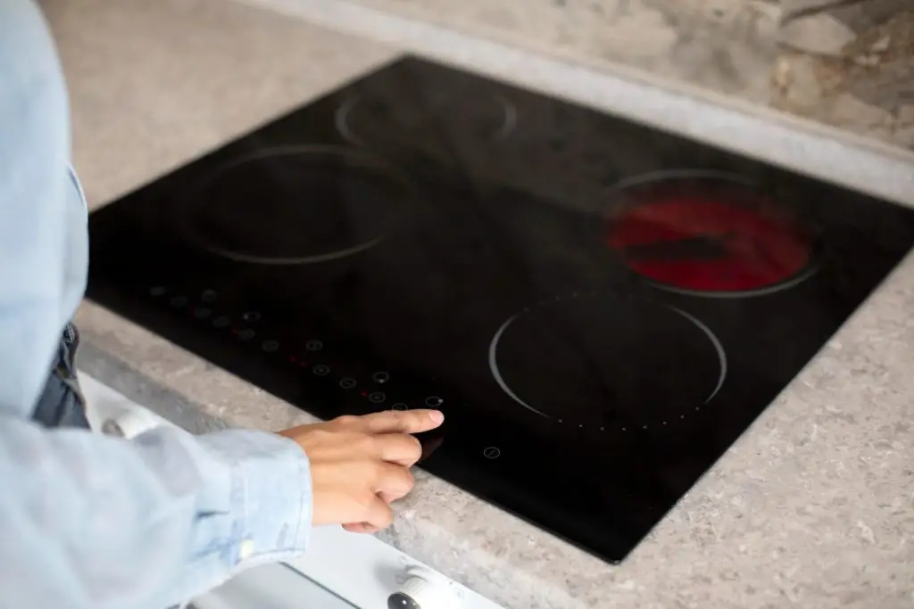 Woman using modern induction hob in the kitchen setting heating power