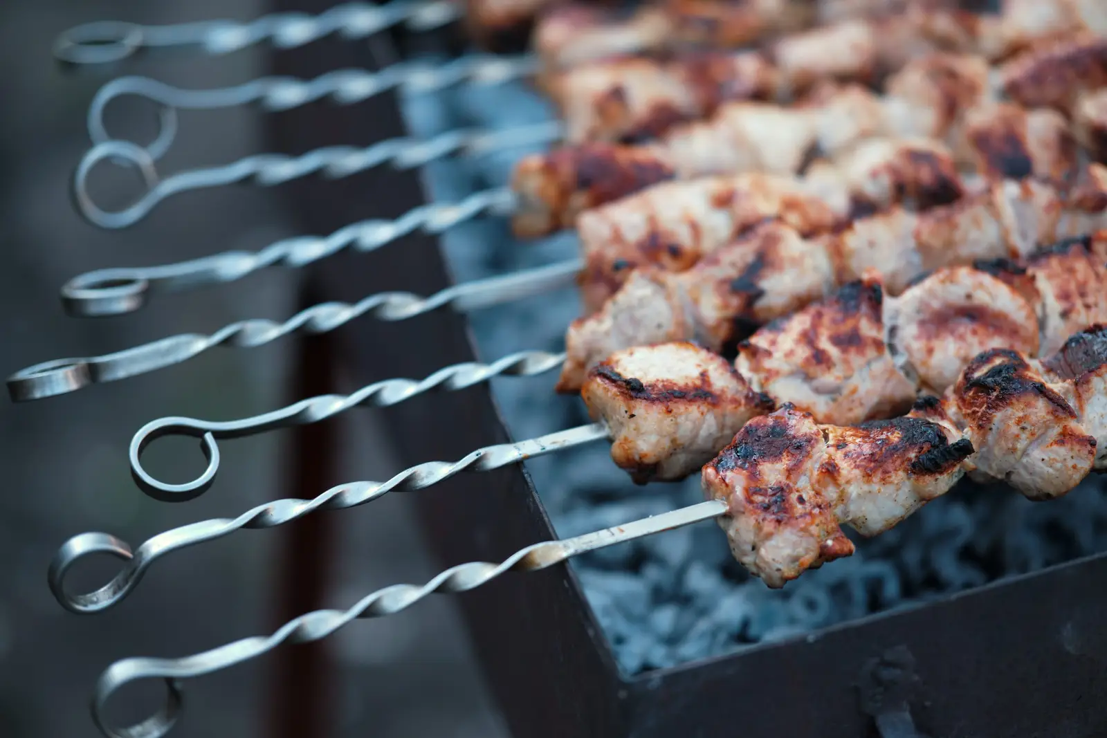 Meat skewers grilling over hot coals — a reminder that wooden skewers are the correct choice for microwave grill cooking