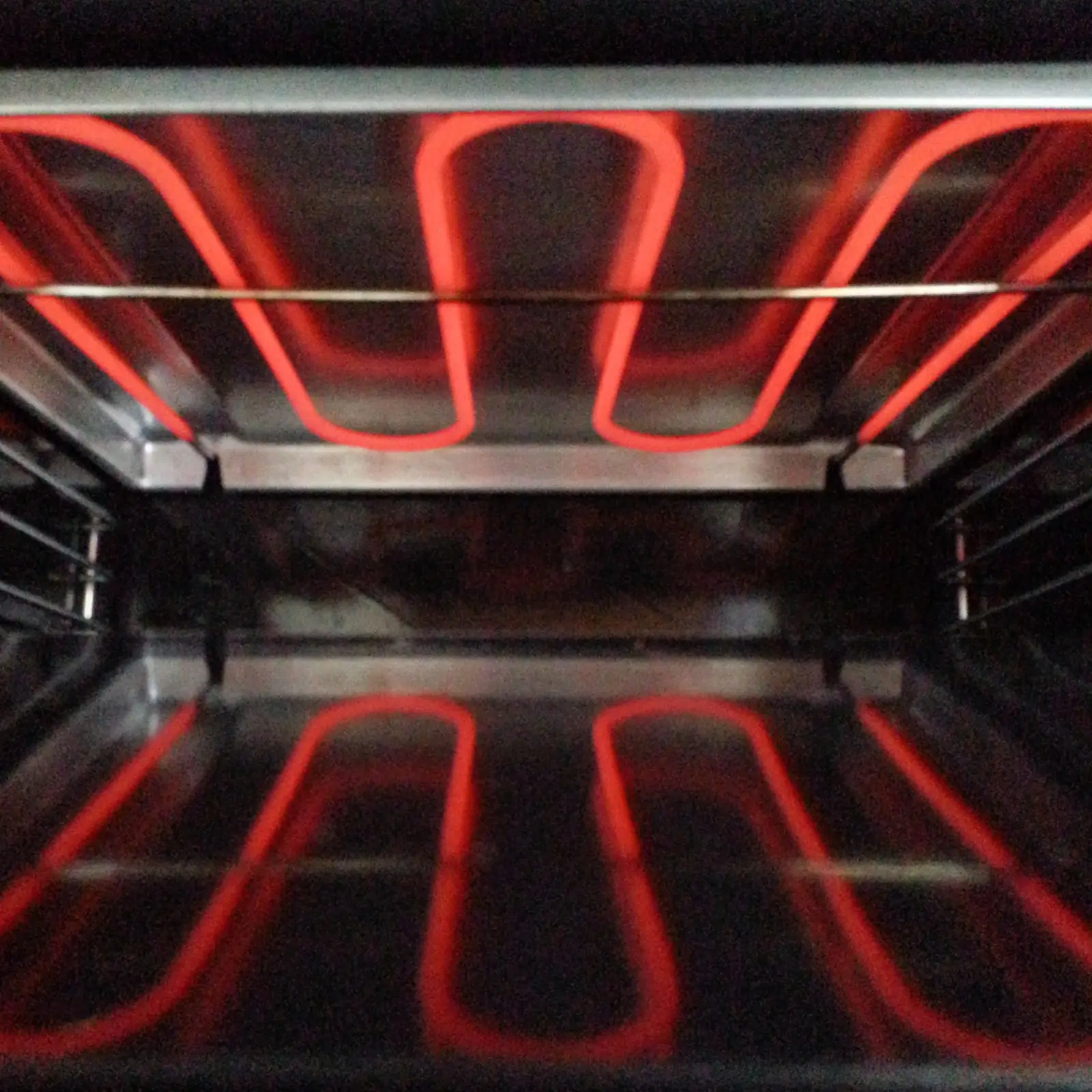 Red glowing oven grill element — a sharp acrid smell with unusual heat or sparking means stop using the oven immediately