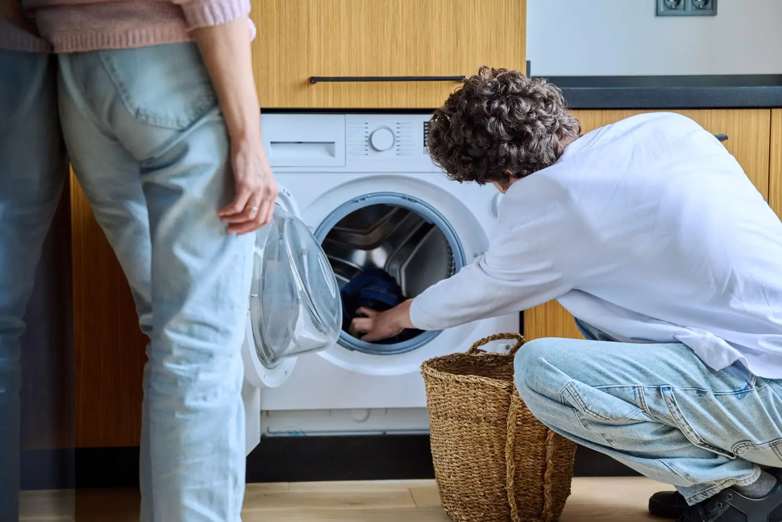 Adults doing laundry at home — a washing machine that stops mid-cycle is usually responding to a drainage blockage, unbalanced load, or water supply issue