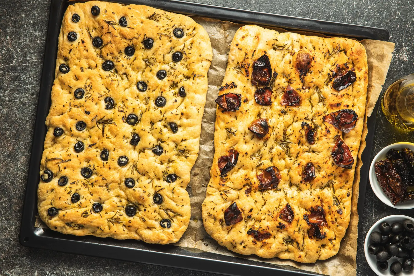Focaccia bread topped with olives and tomatoes with a crisp golden underside