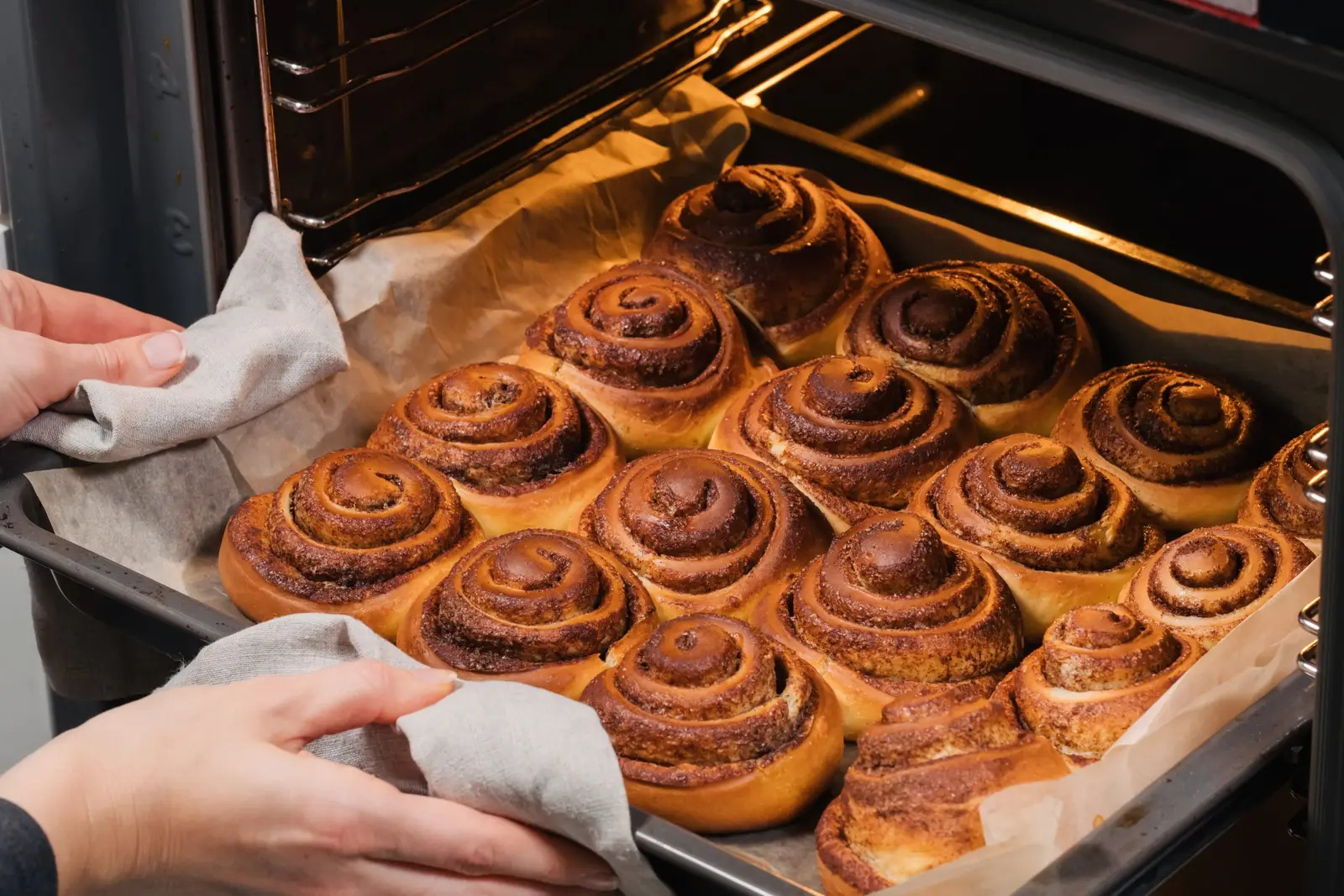 Freshly baked cinnamon rolls turning golden on a tray inside a fan oven