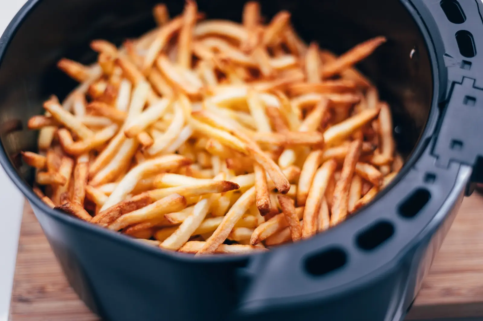 Golden chips freshly cooked in an air fryer basket