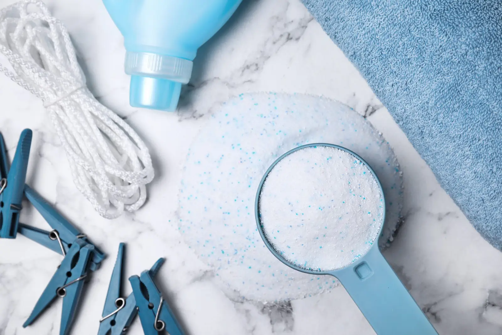 Laundry detergent, capsules and washing supplies laid out on a marble surface