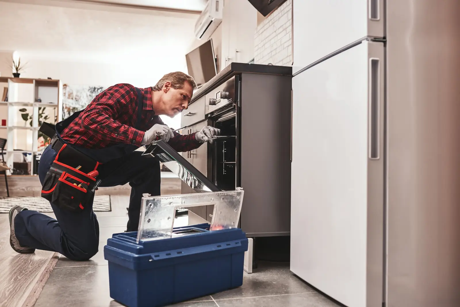 An engineer repairing a built in oven in a kitchen