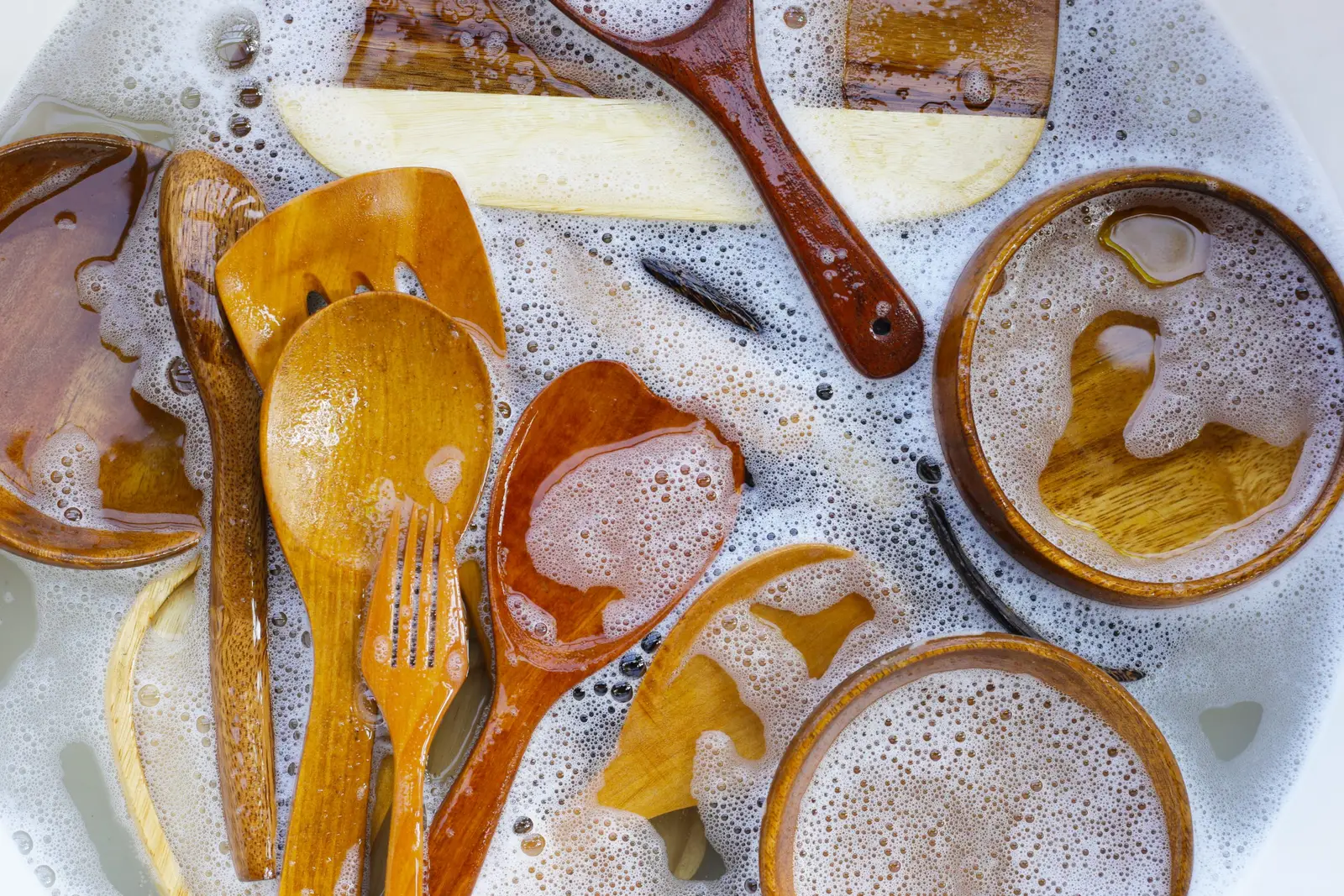 Wooden cooking utensils being hand washed in warm soapy water