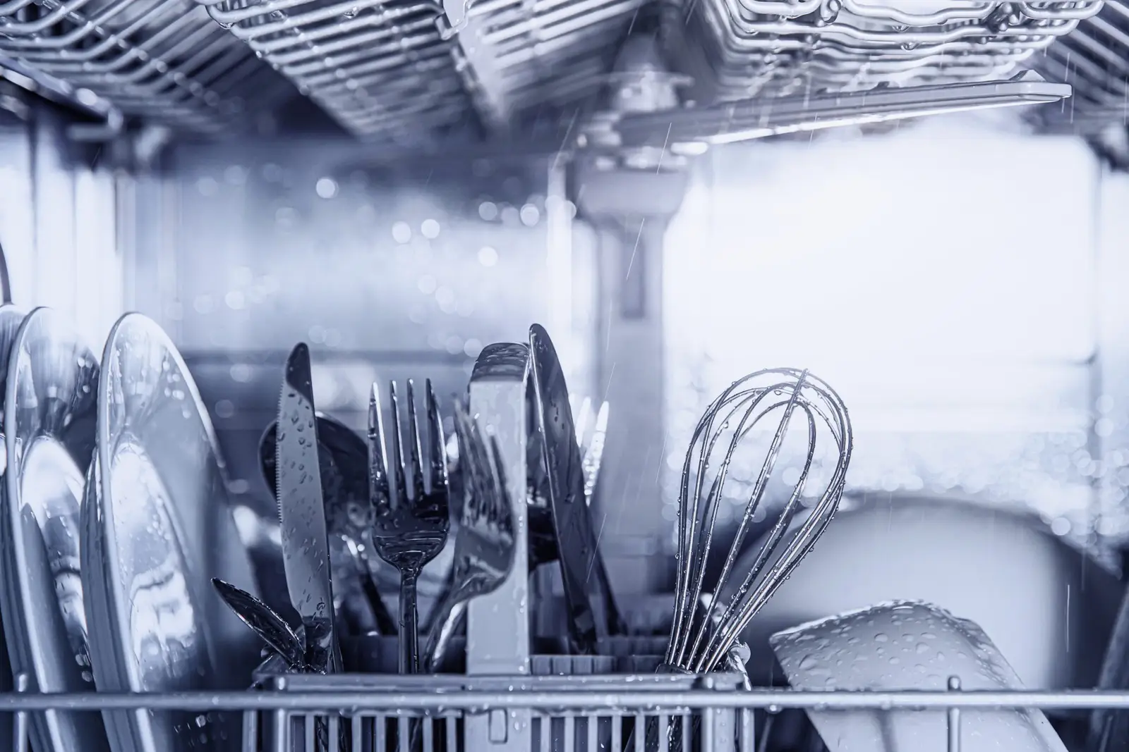 Clean silverware and dishes being washed inside a dishwasher